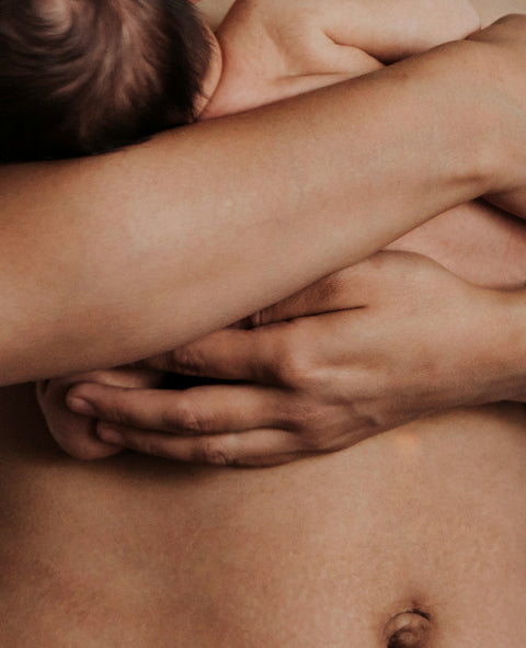 Mutter hält ihr Neugeborenes an ihren nackten Bauch